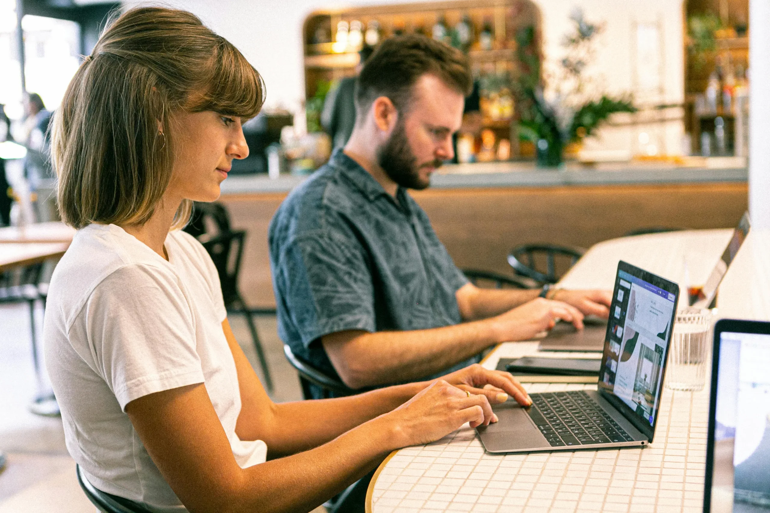  A man and woman using laptops while seated at a table