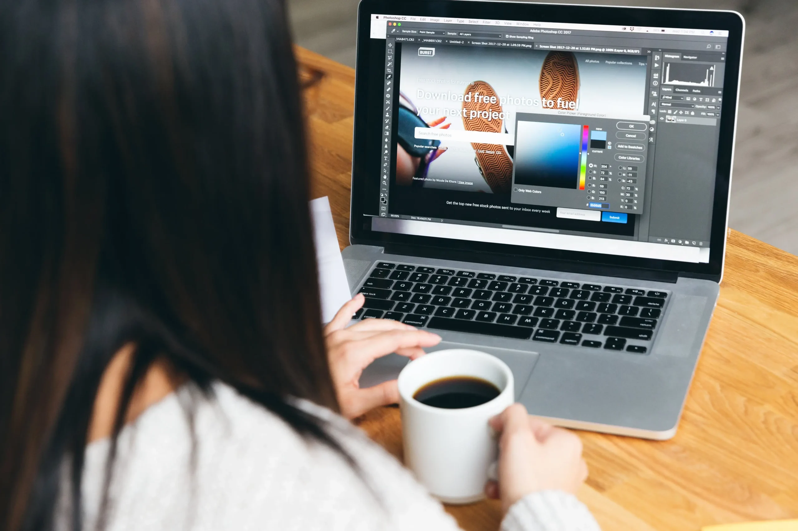 Image of a woman, a freelance graphic designer in Thrissur, using her laptop while enjoying a cup of coffee