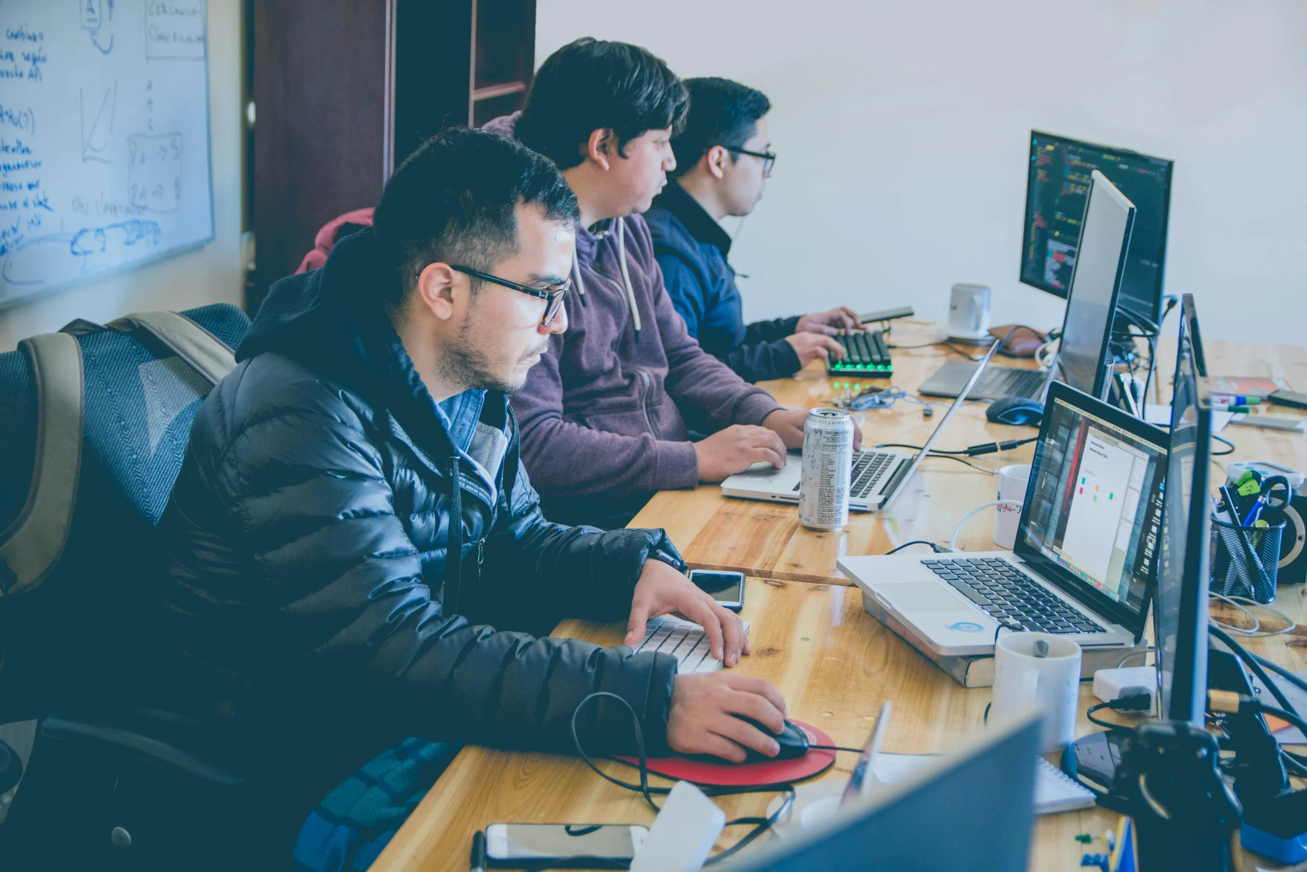 Three professionals using laptops at a desk in graphic designing companies in thrissur